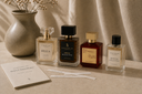 Collection of perfume bottles on a textured surface with a vase and papers.