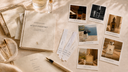 A styled flat-lay of a perfume discovery set featuring a book titled 'SCENE PASSPORT', several polaroid-style fragrance photos, cards, a pen, and small glass bottles on a warm beige fabric surface.